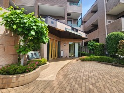 植栽に彩られたアプローチと、ガラス張りで開放感あるエントランスが魅力的。